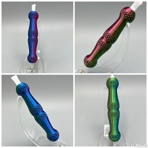 May include: Four iridescent metal tools with a pointed tip and a textured, diamond-shaped pattern. The tools are displayed on clear plastic stands.