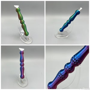May include: Three iridescent, multi-colored, decorative tools with a white tip. The tools are displayed on clear plastic stands. The tools have a textured, patterned surface.