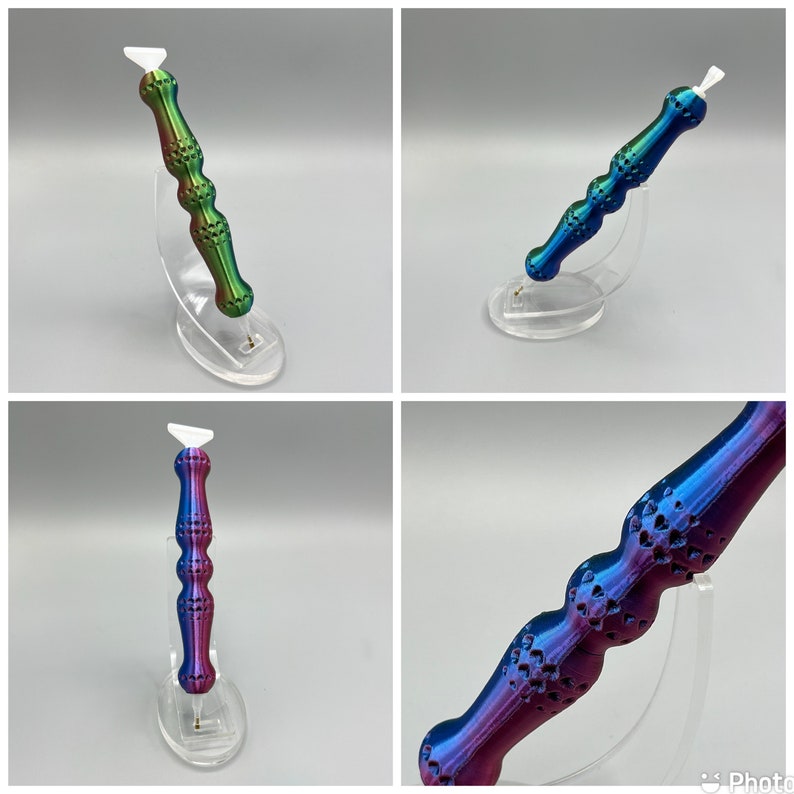 May include: Three iridescent, multi-colored, decorative tools with a white tip. The tools are displayed on clear plastic stands. The tools have a textured, patterned surface.