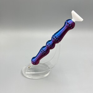 May include: A purple and blue diamond painting tool with a white tip, sitting on a clear plastic stand.
