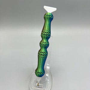 May include: A green, blue, and white diamond painting tool with a textured handle. The tool is made of plastic and has a small, pointed tip.