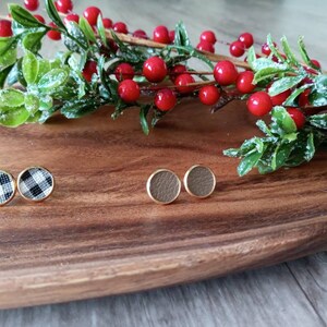 May include: Two pairs of stud earrings. One pair is black and white checkered fabric and the other pair is brown leather.