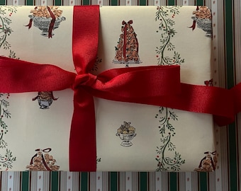 May include: A rectangular gift box wrapped in cream-colored paper featuring a repeating pattern of illustrated food displays and green vines, tied with a wide, vibrant red grosgrain ribbon finished in a centered bow.