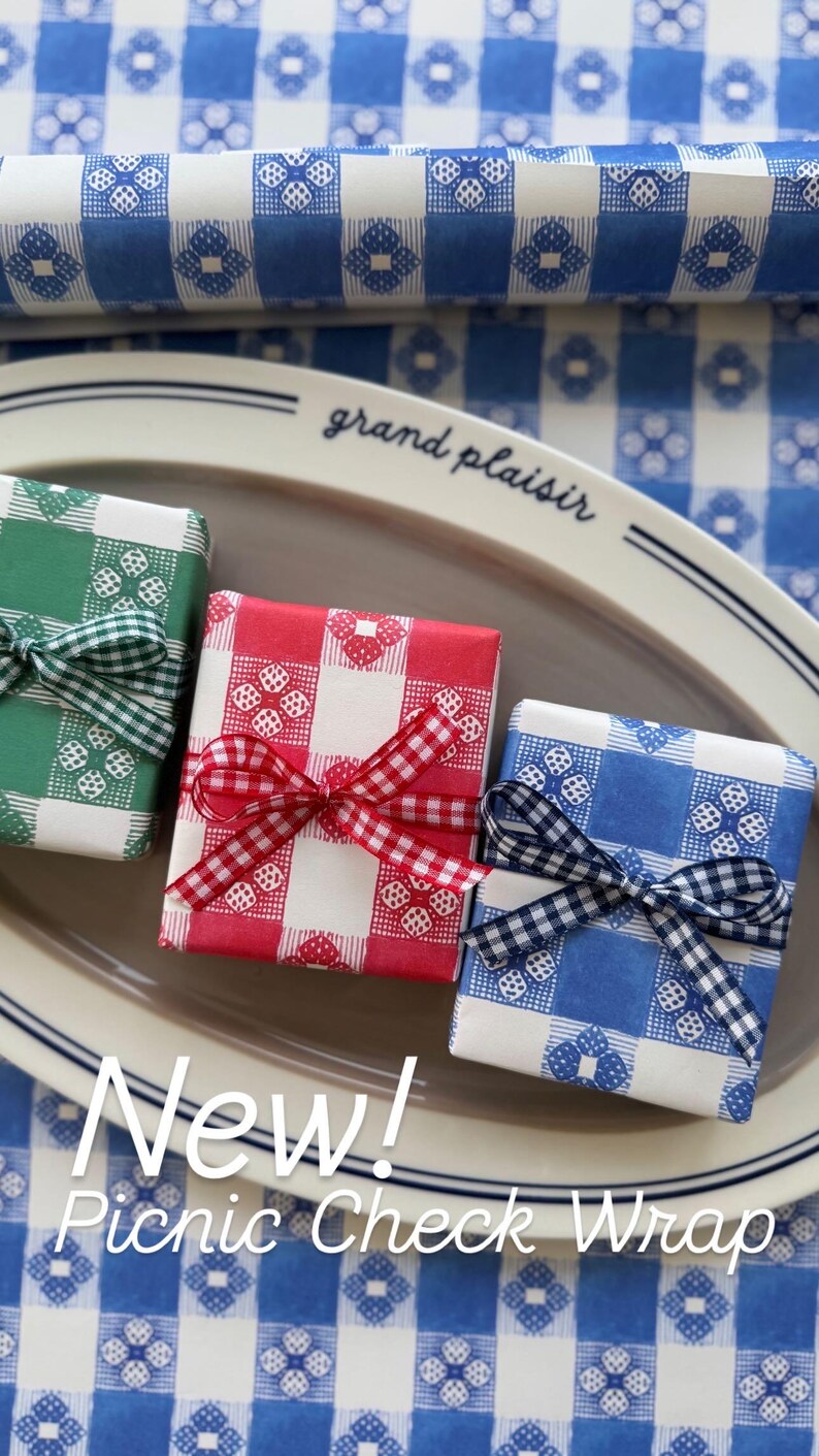 May include: Three wrapped gifts in green, red, and blue picnic check paper, each tied with a matching ribbon. The gifts are on a gray oval platter, with a blue and white checkered background. Text on the image reads "New! Picnic Check Wrap."