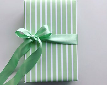 May include: A green and white striped gift box with a green satin ribbon tied in a bow.