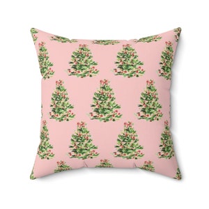 Op de afbeelding: Een roze kussen met een herhalend patroon van groene kerstboom met rode kerstballen.