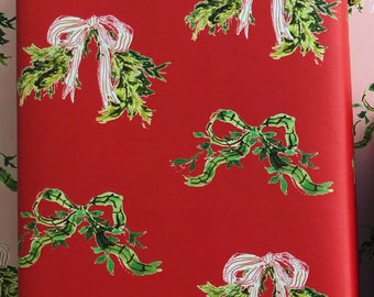 May include: Red wrapping paper with a repeating pattern of green sprigs of holly with white and pink bows.