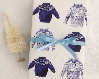 Può includere: Carta da regalo bianca con un nastro blu e un motivo ripetuto di maglioni blu e bianchi ad acquerello.