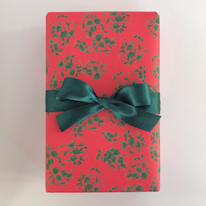 May include: A red gift box with a green floral pattern and a green satin bow.