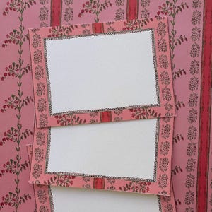 May include: Three rectangular cards with a pink floral border featuring green stems and red blossoms. Each card has a central white rectangular space framed by a hand-drawn black scalloped line, layered over a matching pink floral patterned background.