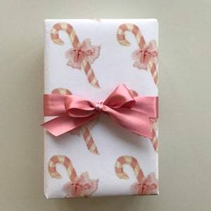May include: A white gift box with a pink ribbon and a pattern of pink and white candy canes.