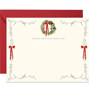 May include: Ivory stationery set with a red envelope. The stationery features a watercolor wreath with a red bow and the text "HOLIDAY GREETINGS FROM ANNA". Decorative red bows and floral accents adorn the corners.