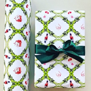 May include: Two rolls of white wrapping paper with a green and red pattern of holly, nutcrackers, and ornaments. The paper is tied with a green ribbon.