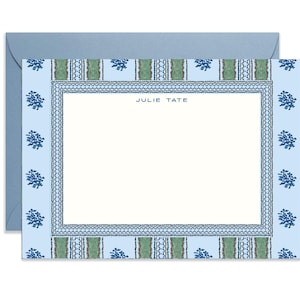 May include: Stationery set featuring a light blue envelope and a matching notecard. The notecard has a white interior with a decorative border in blue and green, and floral accents. The name "JULIE TATE" is printed at the top of the notecard.