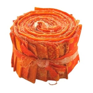 Könnte beinhalten: Eine Rolle mit orangefarbenen Stoffresten, mit einem Band gebunden, bereit für Quilt- oder Bastelprojekte.