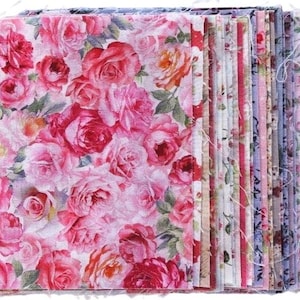Könnte beinhalten: Ein Stapel Stoffquadrate mit einem Blumenmuster. Die Quadrate sind rosa, weiß und grün mit verschiedenen Blumendesigns. Der Stoff ist weich und hat einen Vintage-Look.