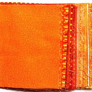 Könnte beinhalten: Ein Stapel orangefarbener Stoffquadrate mit verschiedenen Mustern. Die Stoffquadrate sind in einem Farbverlauf von dunkelorange bis hellorange angeordnet.