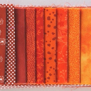 Könnte beinhalten: Eine Sammlung von zehn Stoffstreifen in verschiedenen Orangetönen und Rottönen. Die Stoffstreifen haben unterschiedliche Muster, darunter Punkte, Blumenmuster und geometrische Muster.