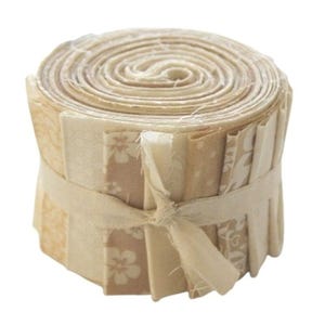 Könnte beinhalten: Eine Rolle Stoffreste in Beige- und Cremetönen, gebunden mit einem beigefarbenen Band. Der Stoff hat verschiedene Muster, darunter florale und geometrische Designs.