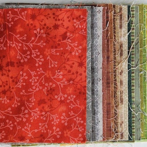 Könnte beinhalten: Eine Sammlung von Stoffquadraten in verschiedenen Brauntönen, Orange- und Grüntönen. Die Quadrate sind in einer Reihe angeordnet, wobei das größte Quadrat in der Mitte ein rotes Blumenmuster aufweist.