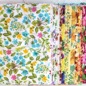 Könnte beinhalten: Ein Stapel bunter Stoffquadrate mit floralen und geometrischen Mustern. Die Stoffquadrate sind in einem Regenbogenmuster angeordnet.