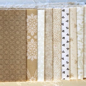 Könnte beinhalten: Eine Sammlung von 10 Stoffstreifen in verschiedenen Beige- und Cremetönen mit unterschiedlichen Mustern, darunter ein Blumenmuster, ein geometrisches Muster und eine einfarbige Farbe.