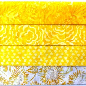 Könnte beinhalten: Vier Streifen gelber Stoff mit verschiedenen Mustern. Der obere Streifen hat ein Blumenmuster, der zweite Streifen hat ein Wirbelmuster, der dritte Streifen hat ein kleines Dreiecksmuster und der untere Streifen hat ein Sonnenblumenmuster.