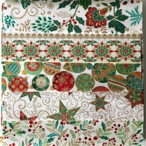 Könnte beinhalten: Ein gefaltetes Stoffstück mit fünf verschiedenen horizontalen Streifen mit Weihnachtsmotiven. Die Designs zeigen Stechpalmenblätter und Beeren, goldene Ornamente, grüne und rote Schneeflocken, bunte Weihnachtskugeln und goldene Sterne.