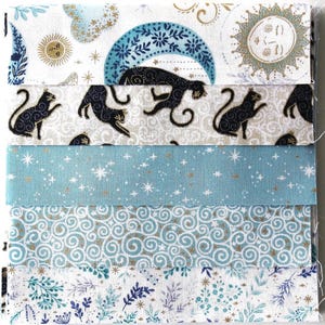 Könnte beinhalten: Ein Stapel aus fünf Stoffmustern mit Himmels- und Katzenmotiven. Die Designs zeigen goldfarbene Sonnen, Monde, Sterne und schwarze Katzen auf weißem, hellblauem und gemustertem Hintergrund mit Wirbelmotiven und botanischen Elementen.