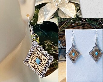 Puede incluir: Pendientes de tono plateado y dorado con una piedra turquesa en el centro de un diseño en forma de diamante.