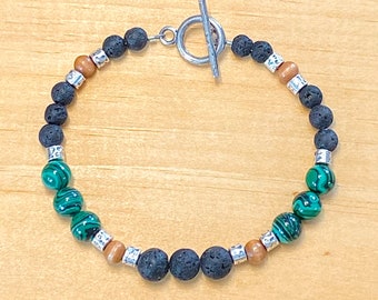 May include: A black lava rock, green malachite, and wood bead bracelet with a silver toggle clasp.