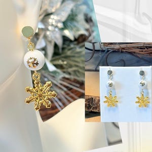 May include: Gold snowflake dangle earrings with a white pearl bead. The earrings are on a white display card.