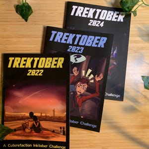 以下が含まれることがあります： 「Trektober」をテーマにした3冊のジャーナル。2022年、2023年、2024年と年号が異なります。ジャーナルは黒い表紙にイラストとテキストが描かれています。2022年のジャーナルは、夕日を眺めるカップルが描かれています。2023年のジャーナルには、疑問符を持った漫画のキャラクターが描かれています。