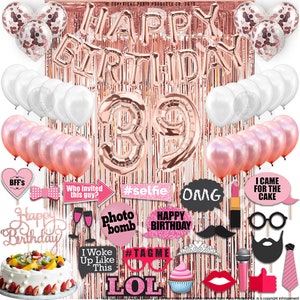 Puede incluir: Decoraciones de fiesta de cumpleaños en oro rosa con globos, una pancarta y accesorios para cabina de fotos. La pancarta dice "Feliz cumpleaños" y el número "39" se destaca.