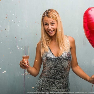 Op de afbeelding: Een vrouw in een zilveren glitterjurk houdt een glas champagne vast en een rode hartvormige ballon met een roze spraakballon waarop "Happy 25th Birthday" staat. Confetti valt om haar heen.