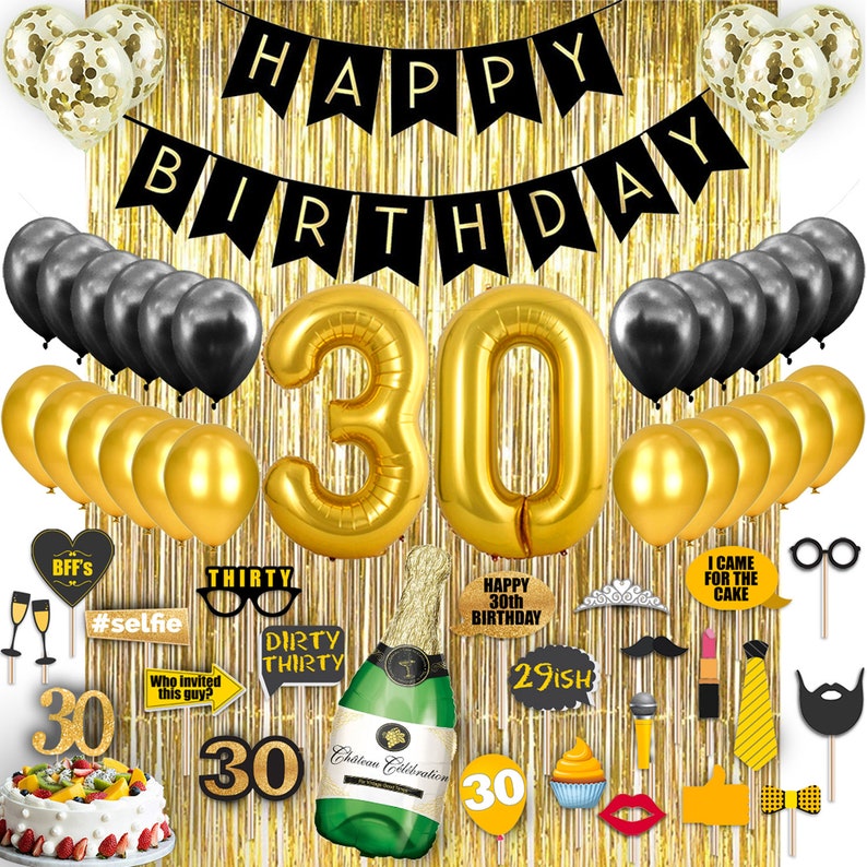 May include: Gold and black 30th birthday party decorations including balloons, a banner, a cake, and photo booth props. The background is a gold foil curtain.