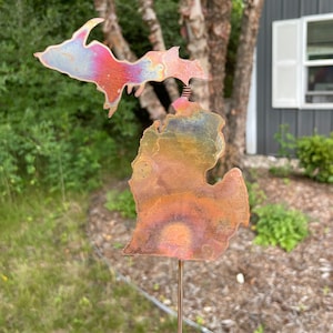 May include: A metal sculpture of the state of Michigan with a colorful, iridescent finish. The sculpture is mounted on a thin metal rod.