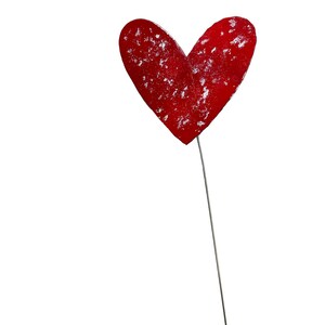 May include: A red heart-shaped decoration with a silver stem. The heart has a textured surface with white accents. The decoration is set against a white background.