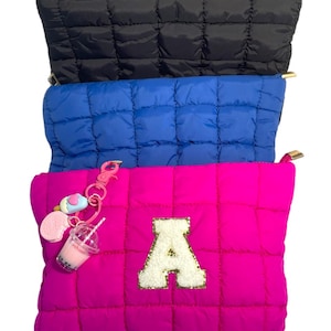 May include: Three quilted zippered pouches in black, blue, and pink. The pink pouch has a white felt letter "A" with gold glitter accents and a charm with a pink heart, a blue popsicle, and a clear boba tea.