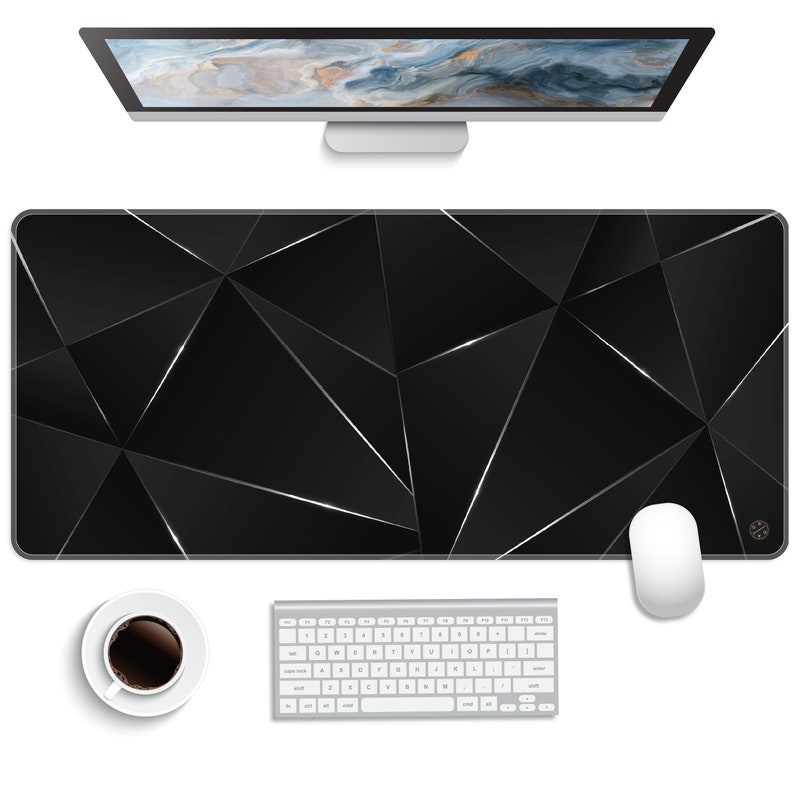 May include: A black and silver geometric design desk mat with a white wireless keyboard and mouse on a white surface.