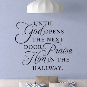 May include: A black and white wall decal with the text "Until God opens the next door, praise Him in the hallway."