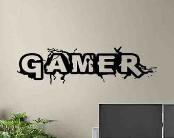 May include: Black and white wall decal with the word "GAMER" in a bold, stylized font. The letters are cracked and broken, creating a grunge effect.