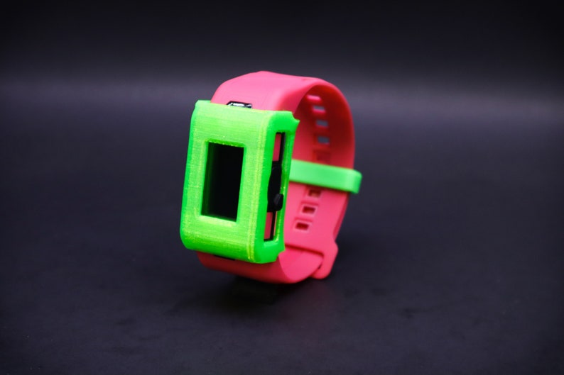 Pode incluir: Uma pulseira de rel&oacute;gio impressa em 3D de cor rosa brilhante e verde com um protetor de tela.