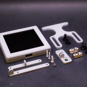 May include: A disassembled electronic device with a white frame and black screen. Components include mounting brackets, screws, and other hardware. The parts are arranged on a dark surface.