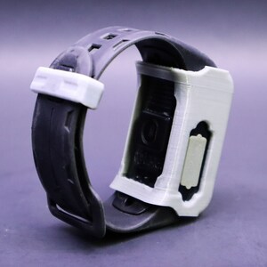May include: A white and black wristwatch with a black strap and a white case. The watch has a rectangular face and a white button on the side.