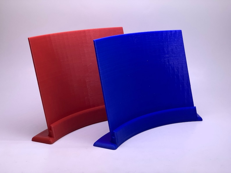 May include: Two 3D printed display stands, one red and one blue, with a curved base and a flat rectangular surface.