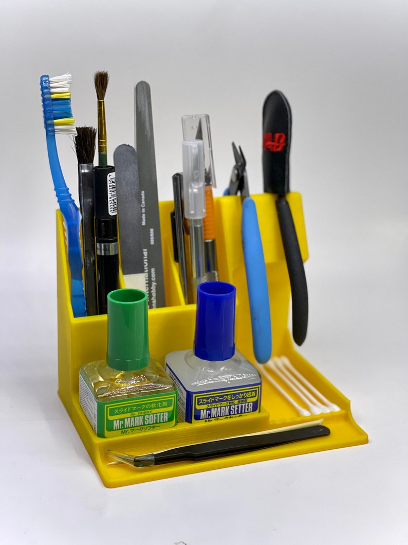 May include: Yellow plastic organizer with various tools for model making, including tweezers, brushes, a file, a hobby knife, a pair of pliers, cotton swabs, and two bottles of liquid labeled "Mr. Mark Softer" and "Mr. Mark Setter".