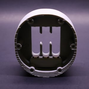 May include: A white plastic round base with three metal prongs protruding from the center. The base has a textured outer edge and a smooth inner surface.