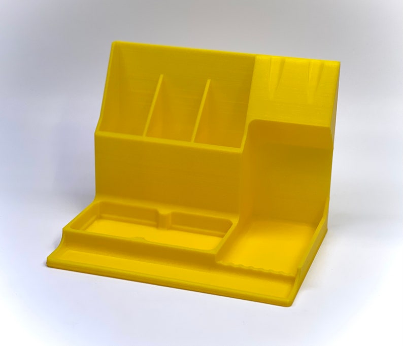 May include: A yellow plastic desk organizer with multiple compartments for pens, pencils, and other office supplies. The organizer has a large tray on the bottom for holding larger items.