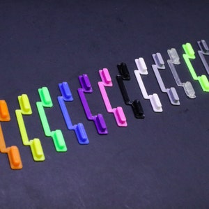 May include: A set of 17 colorful keycaps in a rainbow pattern. The keycaps are made of plastic and have a textured surface. They are arranged in a curved line, with the darkest colors at the bottom and the lightest colors at the top.